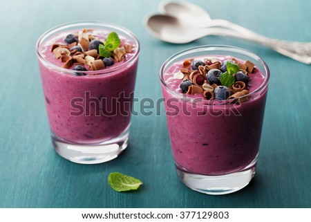 Healthy breakfast of smoothie, dessert, yogurt or milkshake with frozen blueberry and oats decorated grated chocolate and mint leaves on wooden rustic table