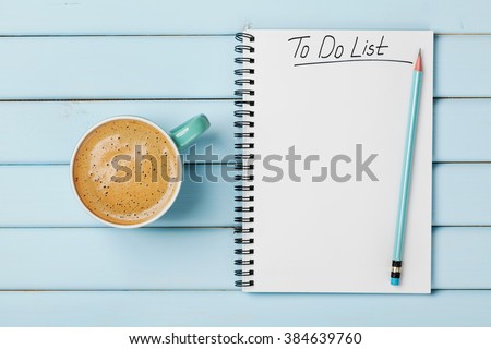 Coffee cup and notebook with to do list on blue rustic desk from above, planning and design concept