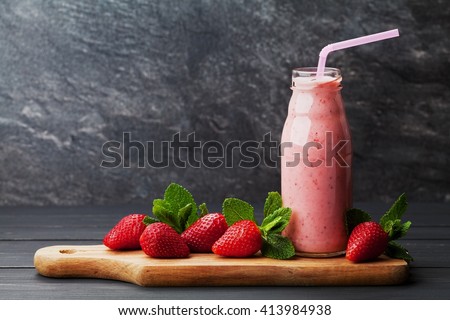 Strawberry smoothie or milkshake in jar on black rustic background, healthy food for breakfast and snack