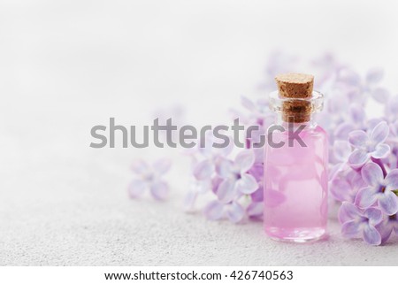 Glass jar with rose water and lilac flowers for spa and aromatherapy, copy space for text