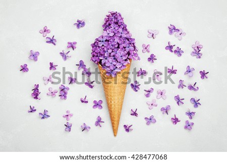 Ice cream of lilac flowers in waffle cone on light gray background from above, beautiful floral arrangement, vintage color, flat lay styling