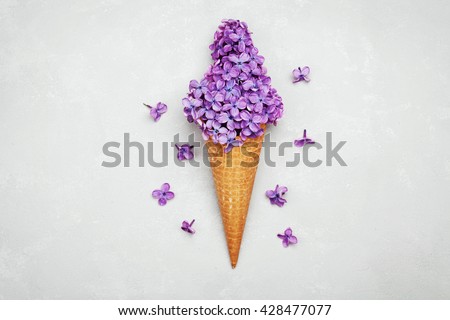 Ice cream of lilac flowers in waffle cone on light gray background from above, beautiful floral arrangement, vintage color, flat lay styling