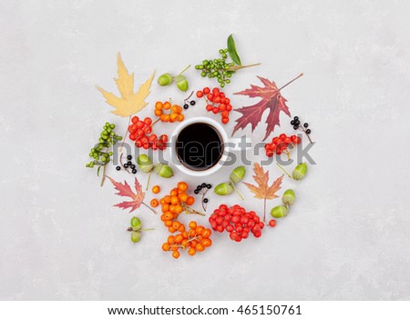 Composition of morning coffee mug, autumn leaves and berry on light background overhead view. Cozy breakfast. Flat lay style.