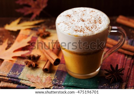 Pumpkin spiced latte or coffee in a glass on a vintage table. Autumn or winter hot drink.