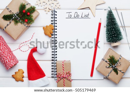 Holiday decorations, gift, present box, miniature fir tree and notebook with to do list on white wooden table from above. Christmas or winter planning concept. Flat lay style.
