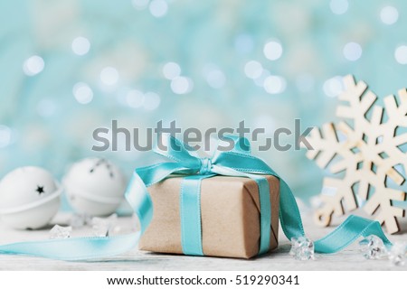 Christmas gift box and white jingle bell against blue bokeh background. Holiday greeting card.