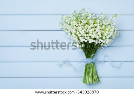 Beautiful bouquet of flowers lily of the valley on  blue wooden table from above.
