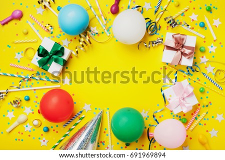 Birthday party background or frame with colorful balloon, gift, confetti, silver star, carnival cap, candy and streamer. Flat lay style. Holiday flyer with copy space.