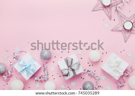Christmas border with gift boxes, balls, decoration and sequins on pink table top view. Flat lay. Copy space for greeting card