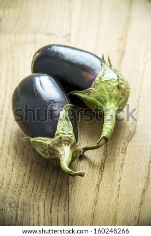 Pair of Eggplants on an old wooden table with swirl leafs