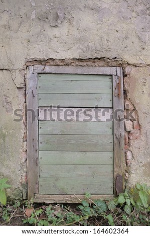 Old wooden access door in the wall, boarded up window