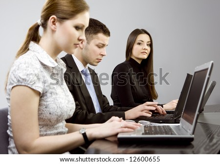 Business group portrait - Young man and two women working together on laptops