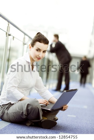 Businesswoman is sitting on the floor with notebook on her lap