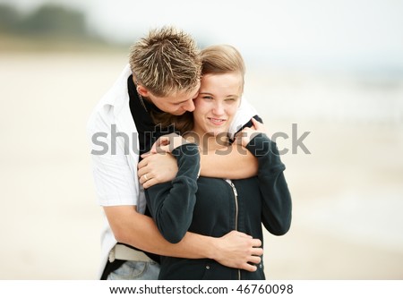 stock photo : two young people walking on the beach kissing and holding 