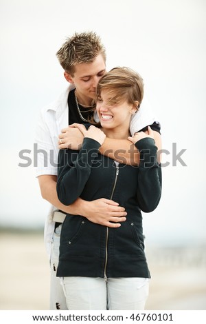 two young people walking on the beach kissing and holding tight