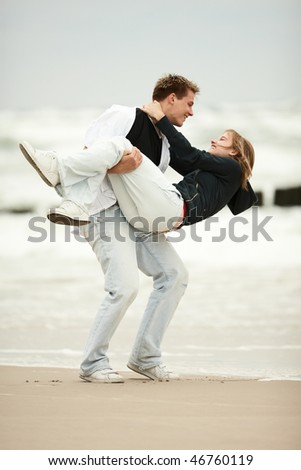 stock photo : two young people playing on the beach  and holding tight