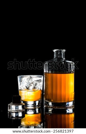 Whiskey on the rocks and a whiskey bottle in dark background