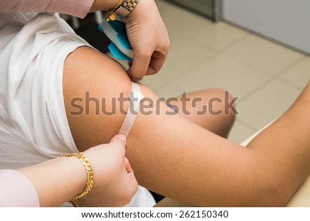 Doctor attaching a plaster onto patient arm after injection