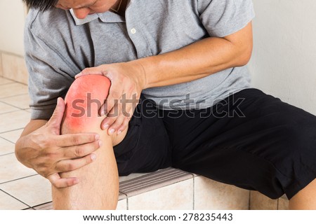 Matured man suffering from painful knee joint seated on steps