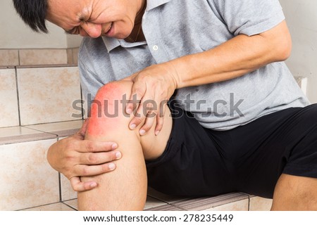 Matured man suffering from painful knee joint seated on steps