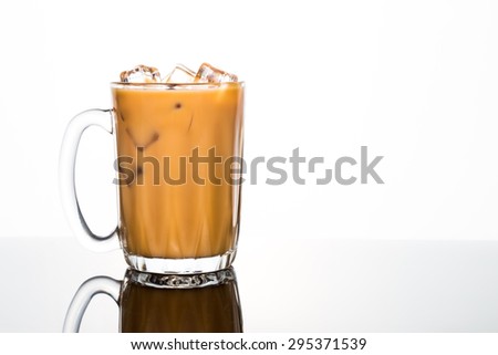 Refreshing ice cold coffee with milk in transparent glass flushed left