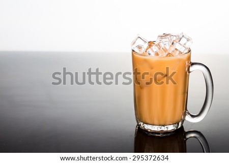 Refreshing ice cold tea with milk in transparent glass flushed right