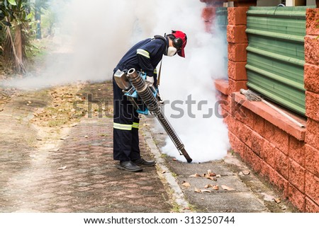 Worker fogging drain at residential area with insecticides to kill aedes mosquito, carrier of dengue virus