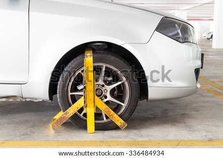Front car wheel clamped for illegal parking, a violation at commercial car parks