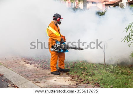 Worker fogging residential area with insecticides to kill aedes mosquito breeding ground, carrier of dengue virus