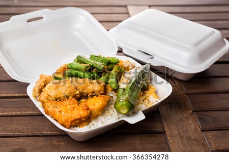 Convenient but unhealthy polystyrene lunch boxes with take away meal on wooden table