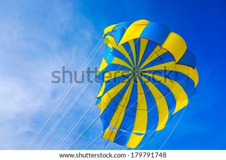 yellow and blue colored paraglider with ropes. high in the sky without person. blue sky with clouds