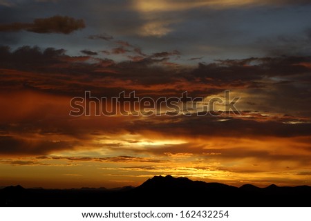 Sun setting over hills with dramatic sky