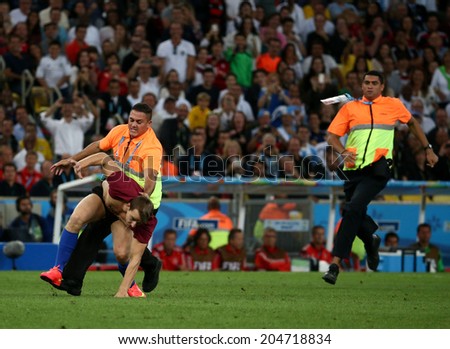 RIO DE JANEIRO, BRAZIL - July 13, 2014: Steward chases pitch invader after entering the field during the World Cup Final game between Argentina and Germany at Maracana Stadium. NO USE IN BRAZIL