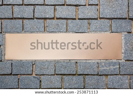 A bronze plaque on the cobblestones. Top view