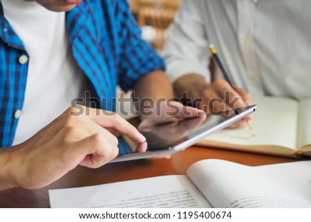 College students are studying and reading together. Have a touch tablet computer for information.