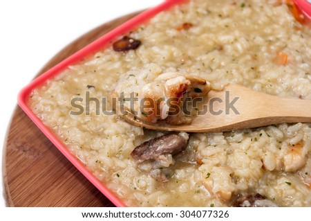 Risotto with meat in a plastic bowl with wooden spoon.
