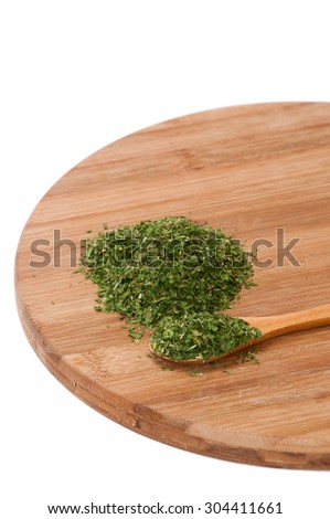 Pile of grounded parsley and on wooden spoon.