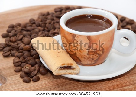 Cookie with fruit filling and a cup of coffee with raw coffee beans.