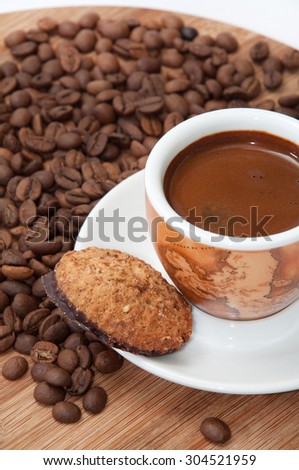 Integrated chocolate cookie and a cup of coffee with raw coffee beans.