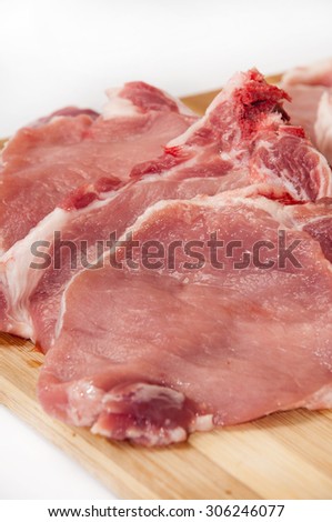 Fresh cut pork chops on wooden board.