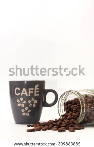 Cup of coffee and spilled coffee beans from glass jar.