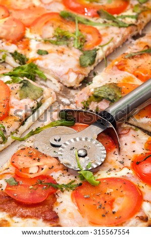 Metal round knife and slices of pizza.