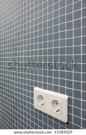 Detail of a double power European electric plug on tiled wall
