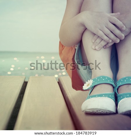 Little girl  sitting on the wooden deck