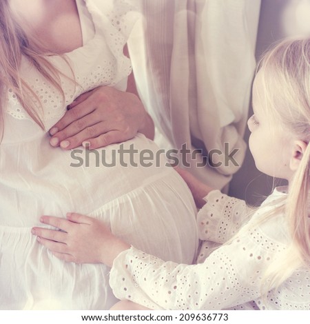 Young pregnant woman with her little daughter Young pregnant woman with her little daughter