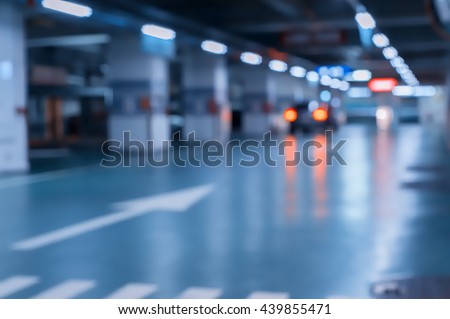 Blurred image/ Parking garage - interior shot of multi-story car park, underground parking with cars.