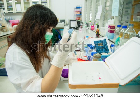 Young female researcher  in white coat loads pcr samples in laboratory