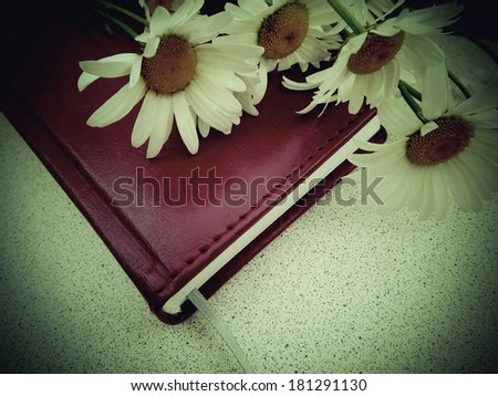 Notebook and daisy flowers. Design in retro style with shallow canvas texture overlay. Filtered image.