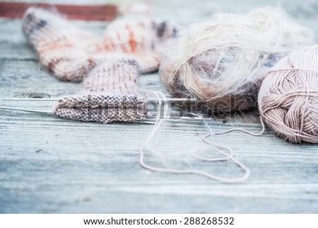 Woolen thread with incomplete knitting socks on vintage wooden background