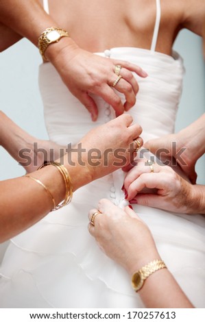 Woman hands helping to place the bride dress. Button from behind.
